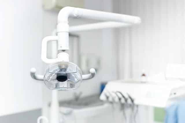 Modern dental operatory chair with overhead light and instruments in professional clinic setting.