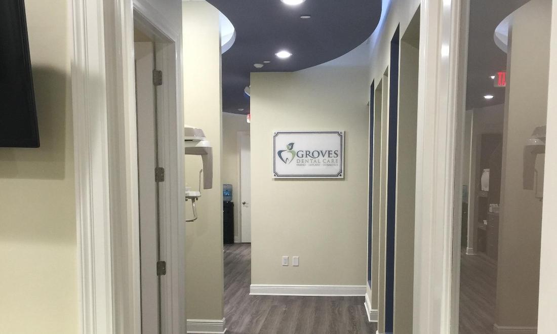 Modern dental office hallway with treatment rooms and Groves Dental Care signage on wall.