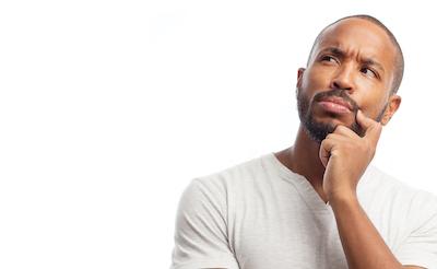 Man in casual shirt thinking thoughtfully with hand to chin against white background