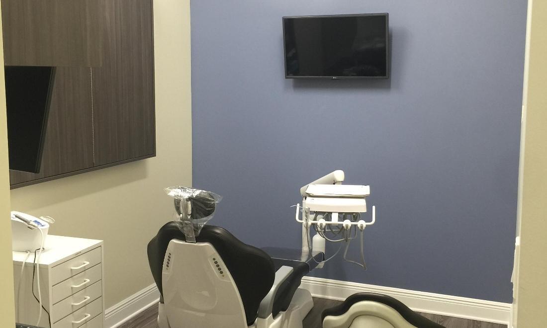 Modern dental operatory with chair, equipment, and monitor in professional clinical setting.