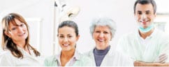 Four dental professionals smiling at camera in modern clinical setting, representing Groves Dental Care team.
