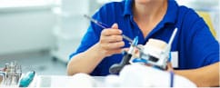 Dental hygienist in blue scrubs performing teeth cleaning procedure in modern dental office.