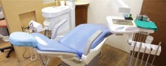 Dental examination room with blue chair, equipment, and supplies at Groves Dental Care clinic.
