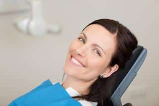Woman smiling in dental chair wearing blue bib at dental office