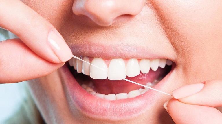 Person flossing teeth, demonstrating proper dental hygiene and oral care technique.