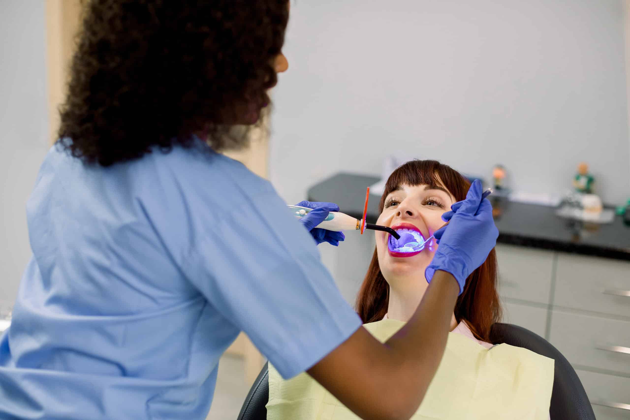 Dental hygienist examining patient's teeth in clinical setting at Groves Dental Care office.